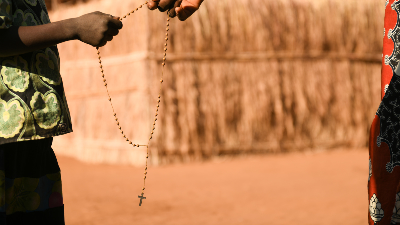 Two hands holding Rosary Beads