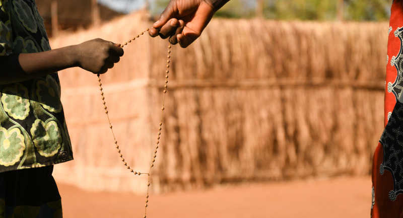 Two hands holding Rosary Beads