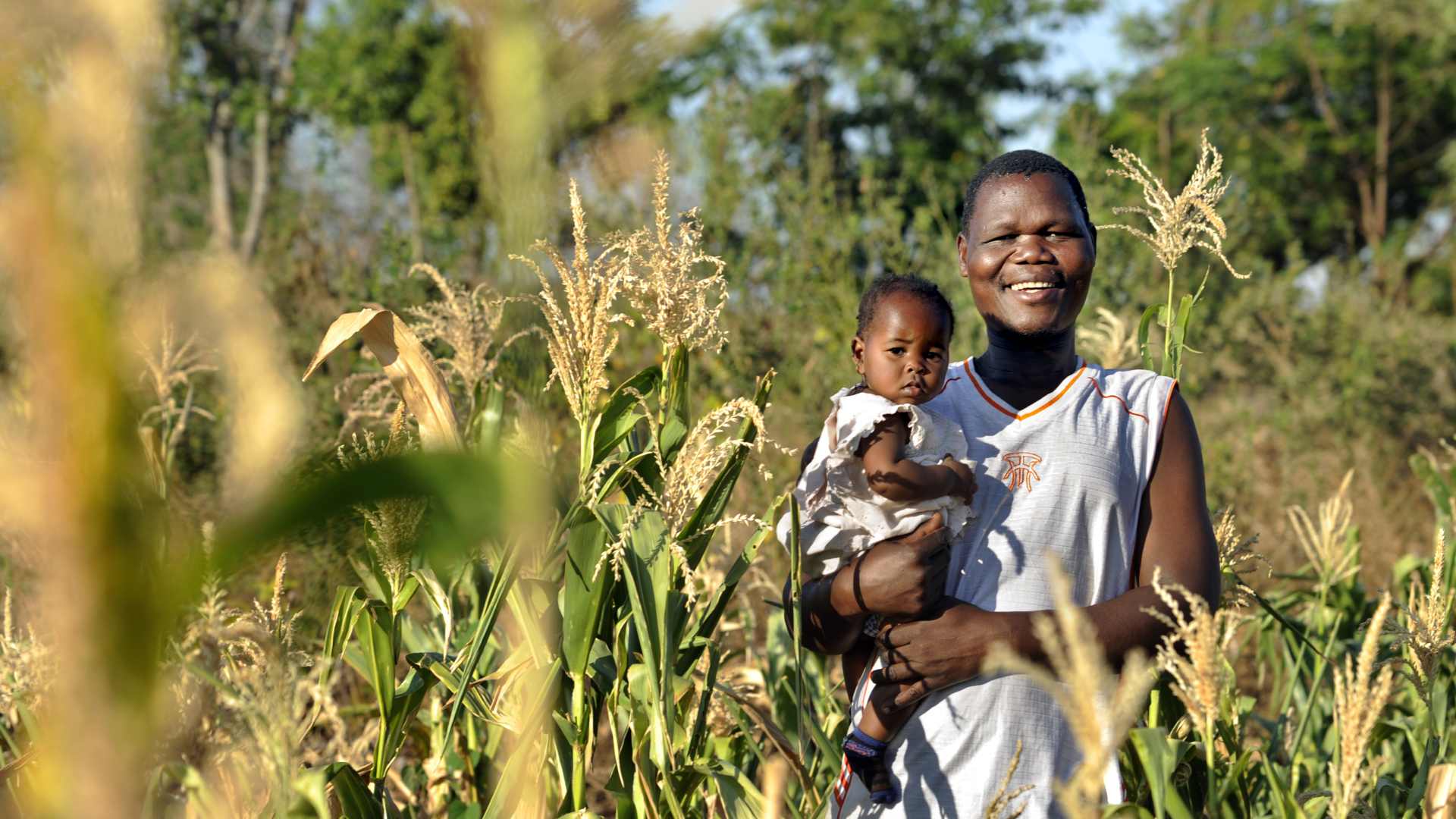 Joseph and his daughter in Malawi smiling at the camera