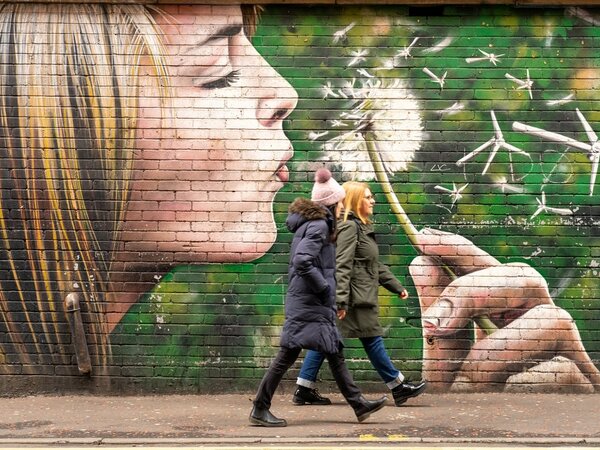 Two people walking past a mural