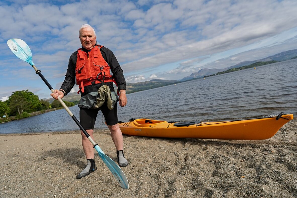 Michael Rainey standing in front of Loch Lomond with a kayak