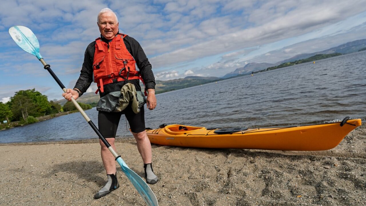 Michael Rainey standing in front of Loch Lomond with a kayak