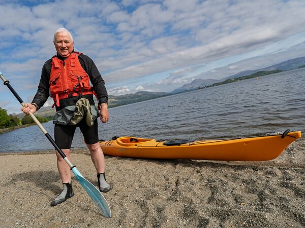 Michael Rainey standing in front of Loch Lomond with a kayak