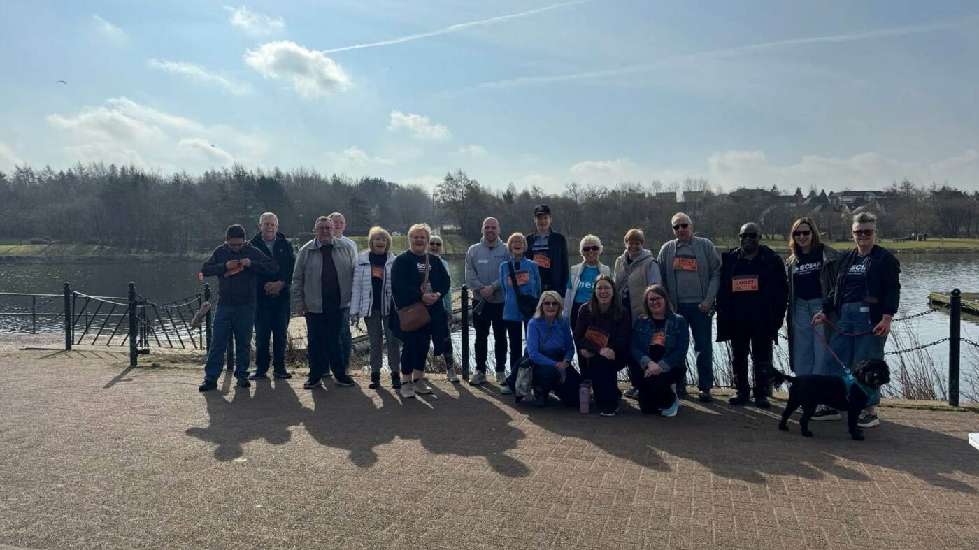 A group of walkers in front of a loch